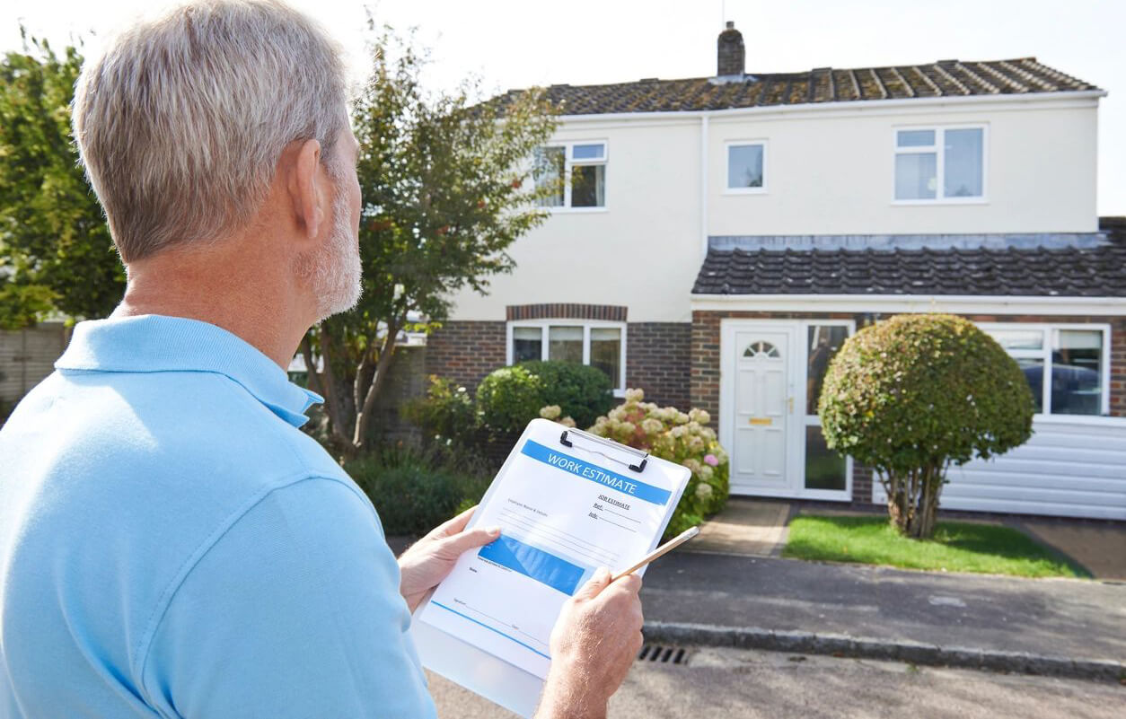 A man providing a work estimate while looking at a house